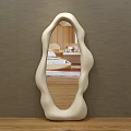 Modern Irregular Shaped Mirror With Cream Frame Reflecting Living Room Interior On Wooden Tabletop