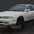 White Old Worn Car With Removed Wheels And Stained Body On Ground
