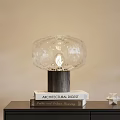 Elegant Crystal Table Lamp With Wooden Base On Books And Star Ornament Against Light Wall