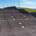 Outdoor Concrete Stairs With Metal Handrails Surrounded By Green Grass And Street Lamps