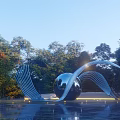 Modern Sculpture Featuring Metal Sphere And Curved Metal Strips In Water With Trees And Lighting