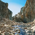Magnificent Natural Rocky Canyon Scenery With Clear Running Stream Under Bright Cloudless Blue Sky