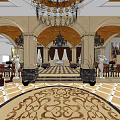 Luxurious Shop Reception Area With Chandelier Columns Statues And Ornate Carpet