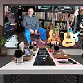 Man Sitting In Room With Guitars Records Speakers Headphones And Audio Gear