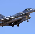 Gray Fighter Jet Flying in Clear Blue Sky With Missiles and Landing Gear Down