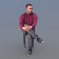 Man Sitting On Chair In Red Sweater Gray Pants Black Sneakers Against Light Blue Background
