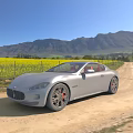 Silver Maserati Sports Car Parked On Dirt Road Near Yellow Flower Field And Mountains