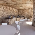 Cave Style Cafe With Stone Walls White Tables Chairs Bar And Sea View Through Window