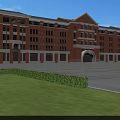Red Brick School Building Featuring Arched Entrance Large Windows and Green Lawn Against Blue Sky