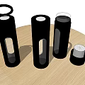 Three Black Insulated Cups on Round Wooden Table with Small Accessory