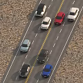 Multiple colored cars driving on the highway with two way lanes and gravel ground