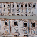 Dilapidated Building Exterior Wall With Broken Windows Peeling Paint Exposed Red Bricks And Decorative Arches