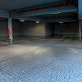 Underground Parking Garage With Gray Paved Floor Red White Striped Columns And Ceiling Lights