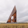Large Rusted Triangular Metal Road Facility In Wheat Field With Person Standing Beside