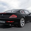 Black BMW Coupe Car With Sleek Design On Open Road And Sky Background