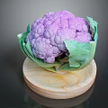 Fresh Purple Cauliflower with Green Leaves Displayed on Wooden Round Board