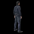 Man Standing in Black Jacket Gray T-Shirt Dark Pants and Gray Shoes on Black Background