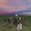 Outdoor Dining Table Setup On Grass Field With Sunset Sky Chairs Lamp And Portable Cooler
