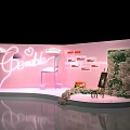 Pink Exhibition Booth With Pendable Neon Sign Chair Easel And Greenery Wall