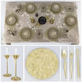 Elegant Dinnerware Set with Gold-Rimmed Plates Glassware and Gold Bow Napkins on Palm Leaf Tablecloth