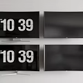 Four Televisions on White Wall with Some Screens Showing Time and Others Blank