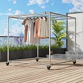 Sturdy Metal Clothes Rack With Wheels Hanging Clothes On Outdoor Balcony With Plants And Sky