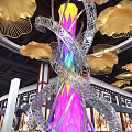 Large Gold And Silver Metal Art Installation With Golden Leaves Purple Light In Mall Interior