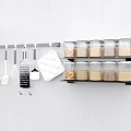 Spice Jars Organized On Black Wall Rack With Kitchen Utensils And Grey Tiled Background