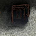 Underground Tunnel Interior With Wooden Support Structures And Rough Rock Walls