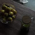 Transparent Glass Bowl With Yellow Fruits And Glass Jug Of Green Liquid On Wooden Tabletop