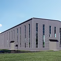 Modern Gray Industrial Factory Building With Large Windows Metal Exterior Green Lawn And Blue Sky