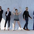 Group of People in Casual and Formal Attire Standing with Diverse Actions Against Gray Wall