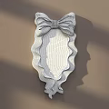 White Decorative Mirror with Bow Shaped Frame Wavy Edges on Light Brown Wall with Shadows