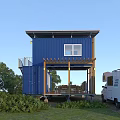 Blue Two Story Container House With Wooden Deck Outdoor Furniture And RV In Green Surroundings