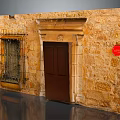 Traditional Stone Building Exterior With Wooden Door Iron Grilled Window And Red Circular Sign