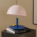 Modern Pink Lampshade Table Lamp with Blue Base on Black Cabinet and Books