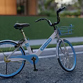 Blue And White Bicycle With Front Blue Basket Parked On Road Near Trees And Houses