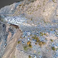 Stone Tunnel Entrance in Mountainous Terrain With Rocks Snow Patches and Slope Path