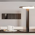 Modern Black Table Lamp With Round Illuminated Shade On Desk Near White Mug