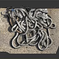 White And Gray Tangled Rope Piled On Textured Mat Beside Brick Wall