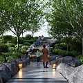 Scenic Park Landscape With Stone Pathway Large Rocks Illuminated Lanterns Green Trees And People Walking