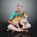 Man With Short Hair Sitting On Floor Holding Brown And White Dog In Green T-shirt