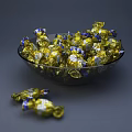 Golden And Blue Wrapped Candies In Transparent Glass Bowl With Scattered Pieces