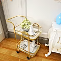 Commercial Serving Cart With Gold Frame Glass Shelves Featuring Green Plants White Tableware