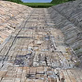 Construction Site Featuring Weathered Concrete Slabs Cracks Green Vegetation Low Hills Under Blue Sky