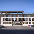 Modern Office Building With White And Dark Exterior Large Windows Spacious Parking Lot And Greenery