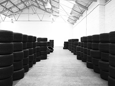 Black and white warehouse interior featuring rows of neatly stacked tires arranged 3d model