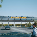 Entrance Gate of Super Racing Stadium with Cars and People in Outdoor Area