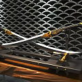 Crossed Swords with Golden Decorations on Black Geometric Wall Illuminated by Lights and Wooden Base