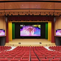 Banquet Hall Interior With Red Seats Stepped Rows Wooden Stage And Lighting Fixtures